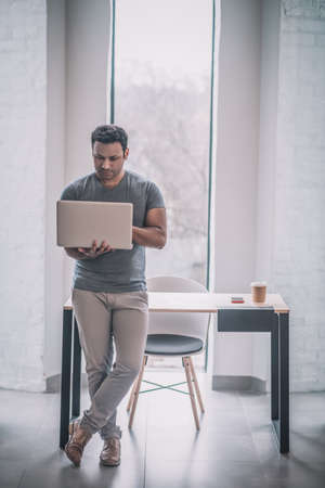 Young businessman working on a laptop and looking contented