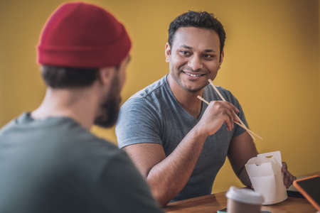 Colleagues having lunch and talking in the kitchenの写真素材