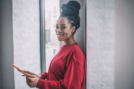 Positive african american woman with a laptop standing near the windowの写真素材
