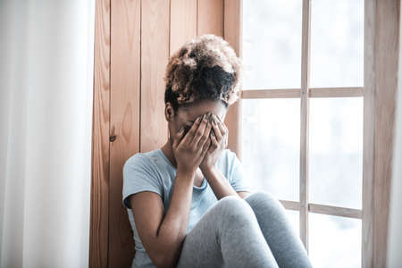 Upset dark skinned woman covering face with handsの写真素材