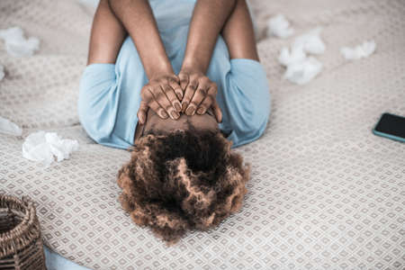 Crying african american woman lying on bedの写真素材