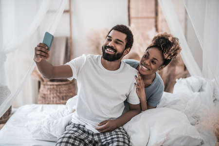 Woman hugging man holding smartphone in outstretched handの写真素材