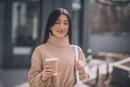 Dark-haired young asian woman with a cup of coffeeの写真素材