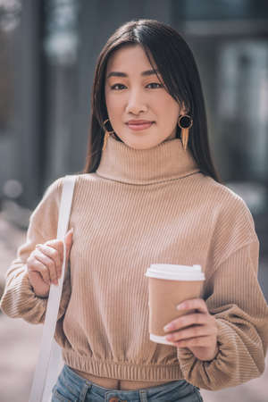 Dark-haired young asian woman with a cup of coffeeの写真素材