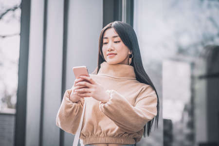 Pretty young asian woman holding a smartphone in her handsの写真素材