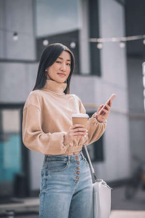 Cute young asian woman holding a smartphone in her handsの写真素材