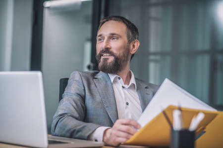 Joyful adult man with folder at table