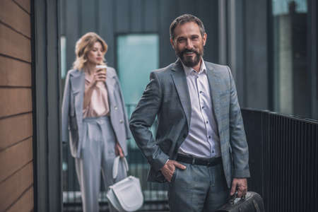Successful business man with briefcase and woman behind
