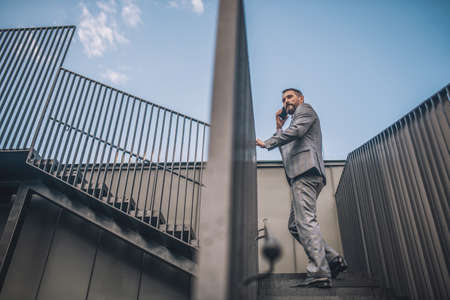 Man with smartphone climbing stairs outdoorsの写真素材