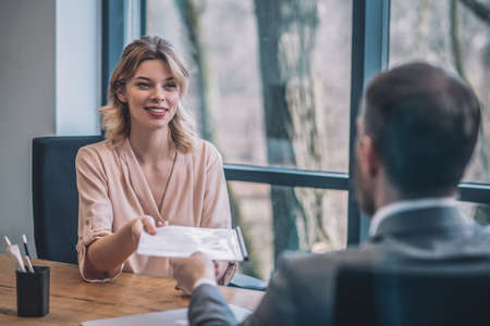 Young pretty business woman taking documents from manの写真素材