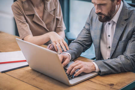 Serious focused man working at laptop and woman handの写真素材