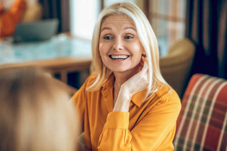 Cute blonde woman spending time with a friend and looking contented
