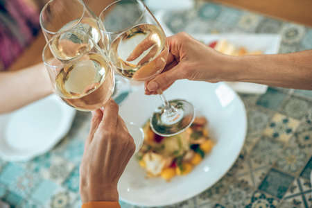 Close up picture of galsses with wine in hands of friendsの写真素材