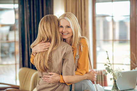 Two friends meeting at the cafe and hugging each otherの写真素材