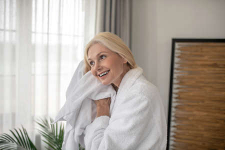 Smiling blonde woman drying her hair with a towel after the bathの写真素材