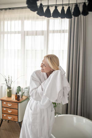 Smiling blonde woman drying her hair with a towel after the bathの写真素材