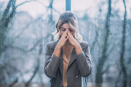 Tired business woman standing with her back to windowの写真素材