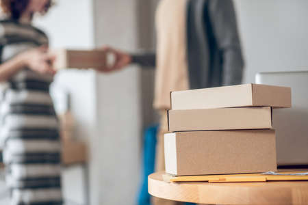 Woman in a striped dress receiving the delivery from a courrierの写真素材