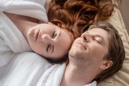 A man and a woman in white looking relaxed and peaceful