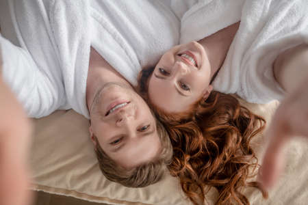 Happy man and woman lying in bed and smiling