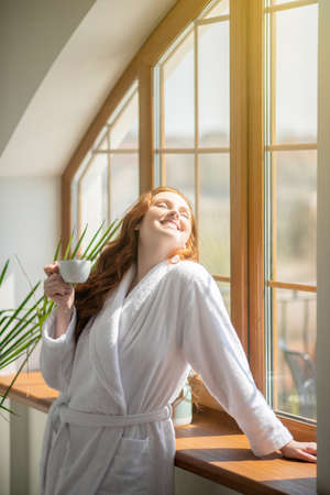 Cute ginger woman in a white bathrobe looking relaxedの写真素材