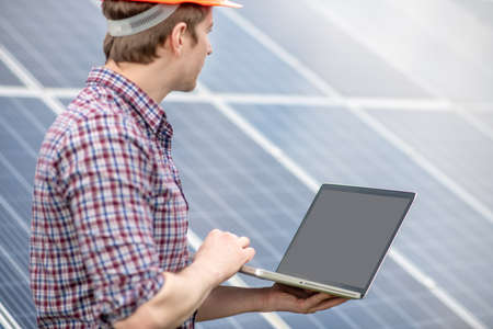 Man looking at surface of solar panelの写真素材