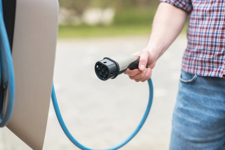 Male hand with cable from wall charging stationの写真素材