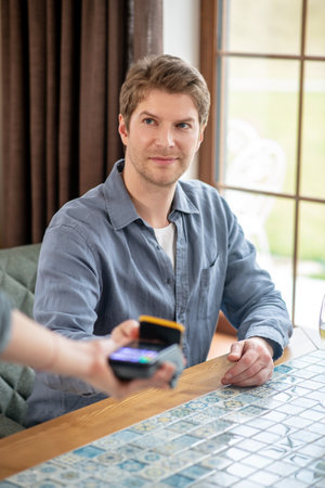 Man holding out smartphone to pos terminalの写真素材