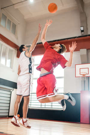 Ginger man in a red sportswear playing basketball