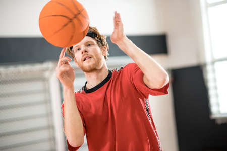 Ginger man in a red sportswear throwing the ball to the basket