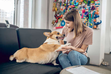 Female pet owner sitting on a sofa with her dog