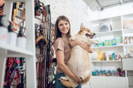 A happy girl and her cute dog in a pet storeの写真素材