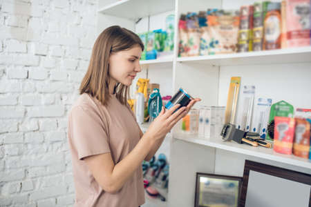 Dark-haired girl choosing nutriments for her pet in a pet storeの写真素材