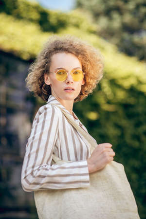 Young woman in sunglasses in the street with eco bag in hands