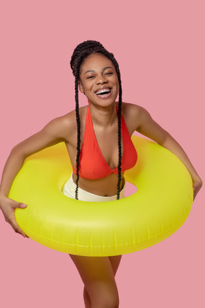 Smiling african american woman holding a yellow tube and having funの写真素材