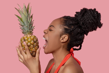 Cute african american woman with a pineapple in handsの写真素材