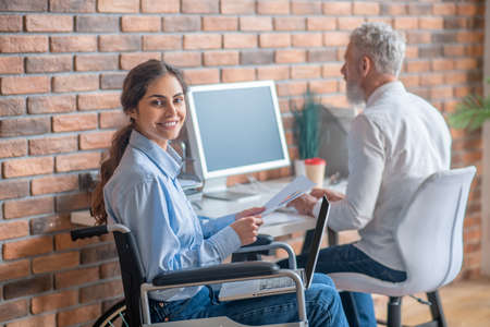 Handicapped young woman working with her colleague in the officeの写真素材