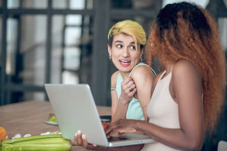 Two girlfriends communicating cheerful in morning in kitchen