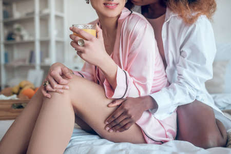 Dark-skinned woman hand on thigh of caucasian girlfriend