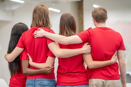 Volunteers hugging standing with their backs to camera