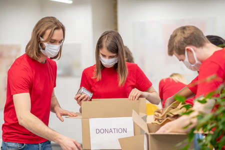 Volunteers wearing protective masks packing donation boxesの写真素材
