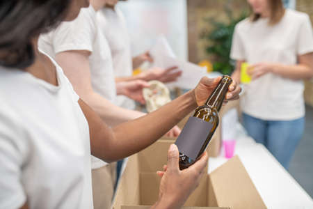 African american woman hands holding bottle over box