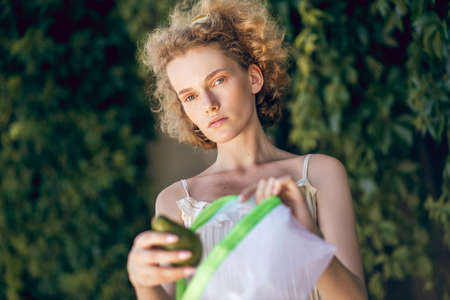 Veggies. A picture of a young cute woman with a pack of veggies in her handsの写真素材