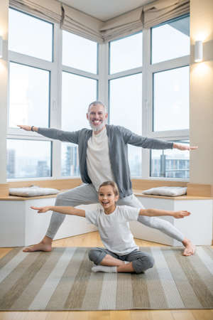 Dad and his kids doing yoga together at home and looking involvedの写真素材
