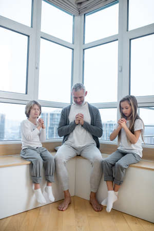 Gray-haired man and his kids sitting peacefully with namaste