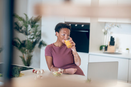 A dark-skinned woman drinking an orange juiceの写真素材