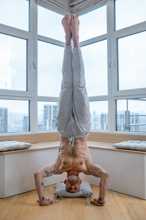 Gray-haired man in a white tshirt doing a headstand