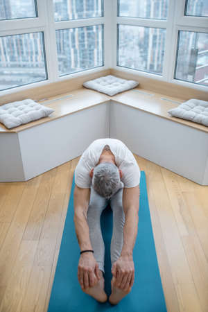 A mature yogi exercising at home and looking flexibleの写真素材