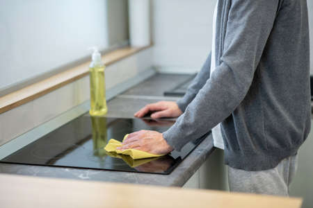 Close up picture of a man cleaning the surface of the table in the kitchenの写真素材