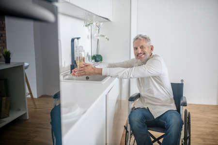 Gray-haired handicapped man in the kitchen getting the breakfast ready